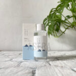 ROUND LAB 1025 Dokdo Toner bottle front view Watery texture of ROUND LAB Dokdo Toner on hand Applying Dokdo Toner with cotton pad on face ROUND LAB 1025 Dokdo Toner packaging featuring deep sea water design